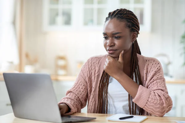 Στρεσαρισμένη μαύρη ανεξάρτητη γυναίκα που κοιτάζει την οθόνη του φορητού υπολογιστή ενώ εργάζεται στο σπίτι — Φωτογραφία Αρχείου