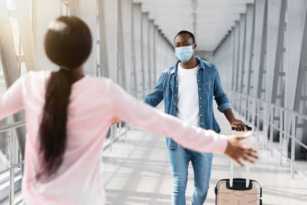 Hombre negro con máscara corriendo para abrazar a su novia después de su llegada al aeropuerto —  Fotos de Stock