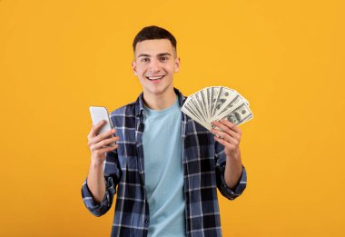 Çevrimiçi finans kavramı. Bin yıllık erkek cep telefonu ve turuncu arka planda Amerikan doları.