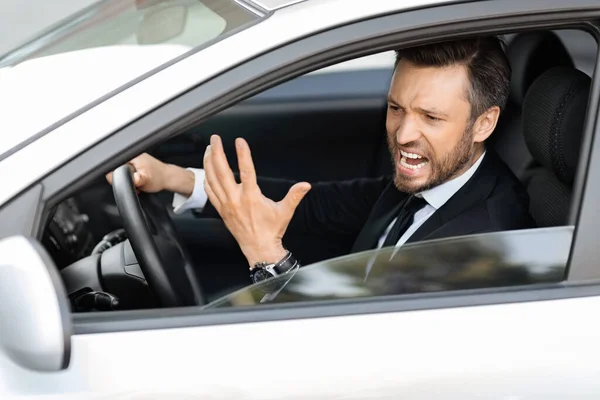 Expressive middle-aged businessman screaming while driving car — Stock Photo, Image