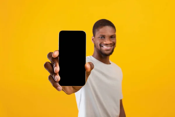 휴대 전화는 흉내를 내고 있습니다. 스마트폰으로 빈 화면을 보여 주며 모바일 앱을 추천하는 행복 한 흑인 남자 — 스톡 사진
