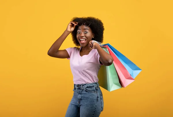 お客様。明るいショッピングバッグ、黄色の背景を持つ感情的なアフリカ系アメリカ人女性 — ストック写真