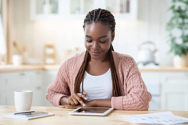 Retrato de sorrir jovem preto feminino relaxante com tablet digital na cozinha, — Fotografia de Stock