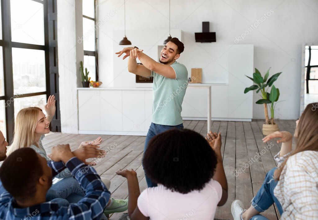 Group of happy multiracial friends playing charades guessing game at home