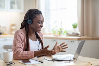 Web Konferansı. Kulaklıklı neşeli Afrikalı kadın laptopla video görüşmesi yapıyor.