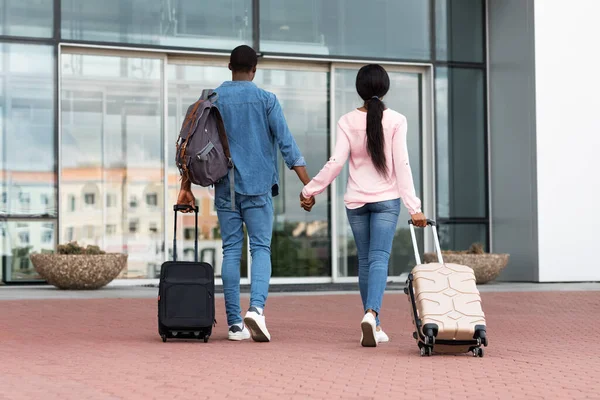 Prêt pour le voyage. Vue arrière du couple noir avec bagages entrant dans l'aéroport — Photo