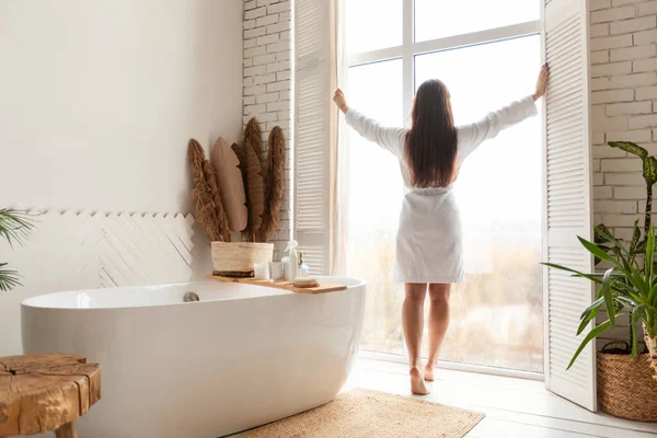 Mujer abriendo ventanas en el baño de pie de nuevo a la cámara interior —  Fotos de Stock