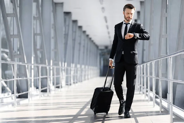 Geschäftsmann mittleren Alters läuft am Flughafenterminal vorbei und kontrolliert die Uhrzeit — Stockfoto