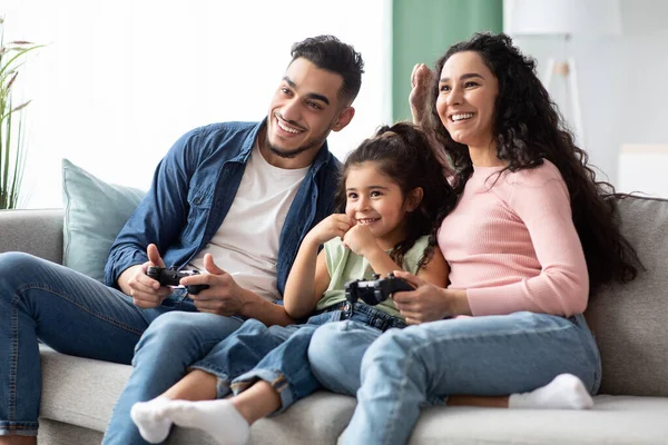 Fröhliche arabische Familie, Eltern und kleine Tochter wetteifern in Videospielen — Stockfoto