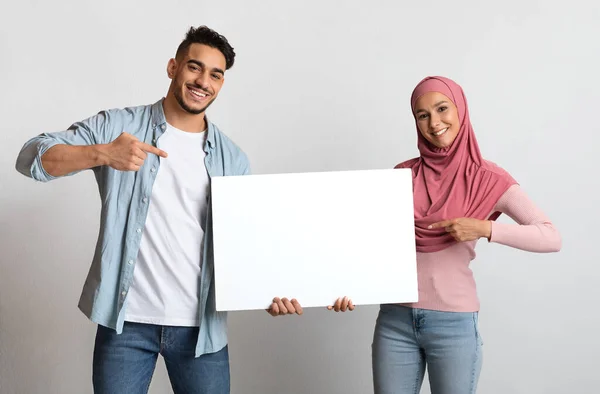 광고를 위한 자리. 블 랜 화이트 플래카드를 들고 행복 한 젊은 이슬람 부부 — 스톡 사진