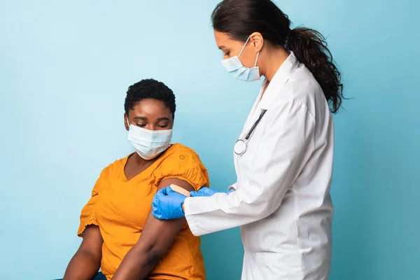 El doctor se pega el vendaje después de la inyección de la vacuna en el brazo de los pacientes, estudio —  Fotos de Stock