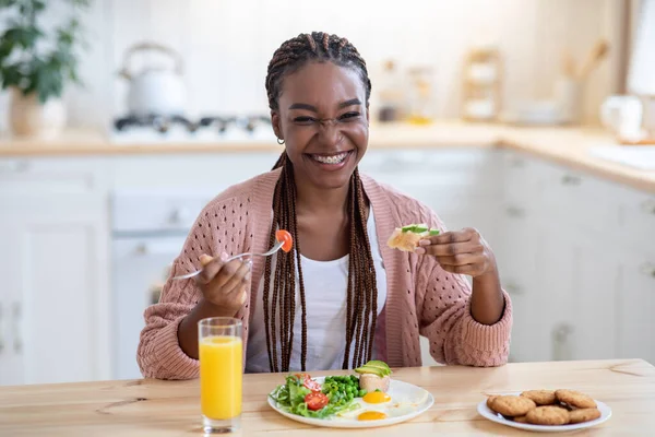Dieta sabrosa. Retrato de alegre joven negro mujer comiendo desayuno en la cocina —  Fotos de Stock