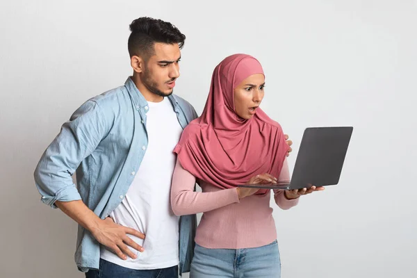Escroqueries sur Internet. Confus jeune couple musulman regardant l'écran d'ordinateur portable avec inquiétude — Photo