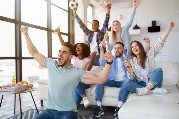 Gruppe junger multiethnischer Freunde schaut Fußballspiel mit Snacks und Bier im Fernsehen und feuert ihre Lieblingsmannschaft zu Hause an — Stockfoto