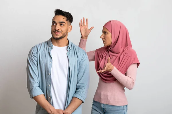 Недопонимание в отношениях. Молодая мусульманская пара спорит, женщина в хиджабе обвиняет мужа — стоковое фото