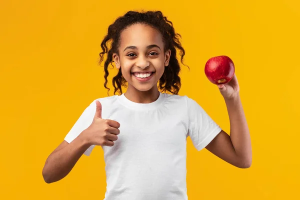 一个拿着红苹果的快乐黑人女孩的画像 — 图库照片