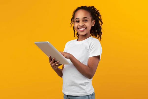 Black girl standing with tablet at yellow studio — Stock Photo, Image
