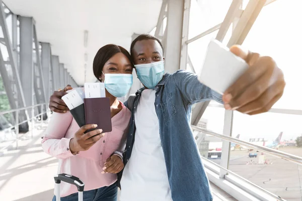 Concepto de vacaciones pandémicas. Pareja negra en máscaras médicas tomando selfie en aeropuerto —  Fotos de Stock