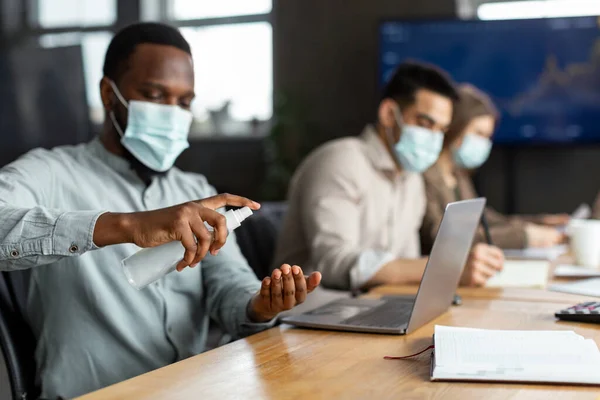 Trabalhadores internacionais usando máscaras médicas usando desinfetante — Fotografia de Stock