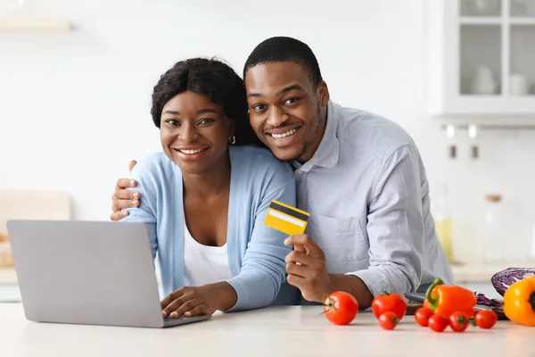 Glückliches schwarzes Paar mit Laptop und Kreditkarte in Küche — Stockfoto