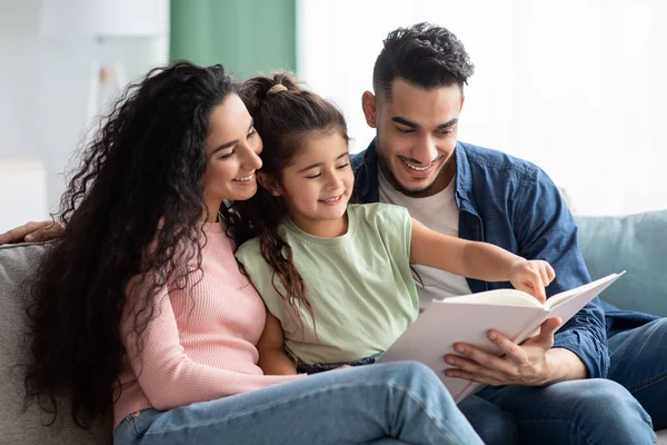 Föräldrakoncept. Glada unga arabiska föräldrar Läsa bok med sitt barn — Stockfoto