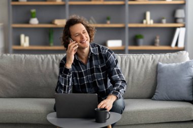 Serbest Çalışan Adam telefonda konuşuyor. Evde oturuyor.