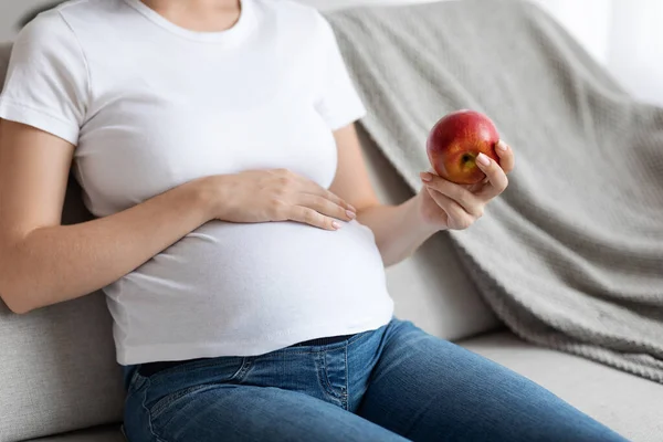 Nutrición prenatal. Primer plano de la señora embarazada sosteniendo manzana roja y abrazando el vientre — Foto de Stock