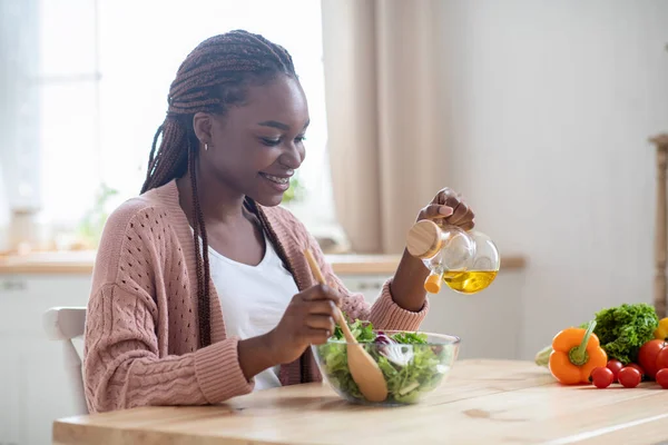 Счастливая молодая черная леди готовит салат из овощей на кухне — стоковое фото
