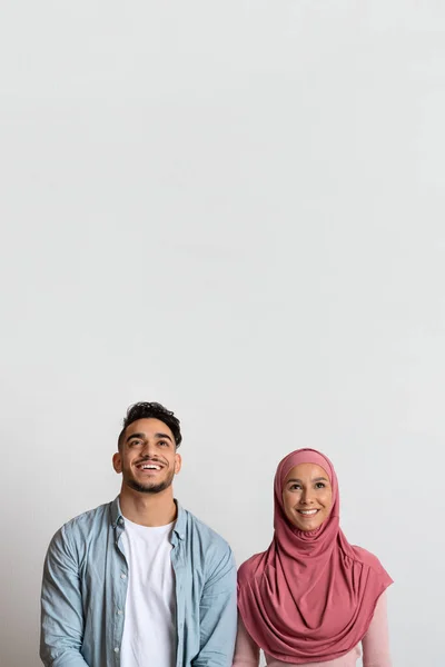 Happy arab man and woman in hijab looking up at copy space — Stok Foto