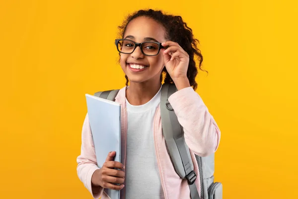 Allegro giovane ragazza nera in possesso di libri di testo guardando la fotocamera — Foto Stock