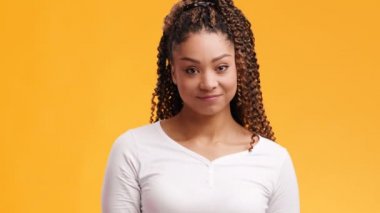 Afro saç stili olan, utangaç ve utangaç, turuncu arka plan, ağır çekim