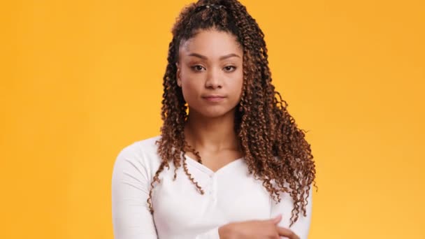 Young pensive african american lady thinking and playing with her braid, orange studio background, slow motion — Stock Video