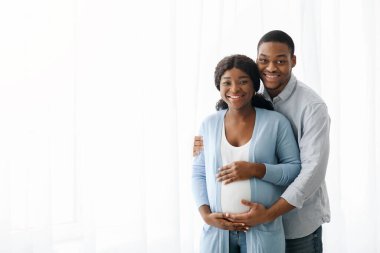 Mutlu siyah çift bebek bekliyor, beyaz arka planda poz veriyorlar.