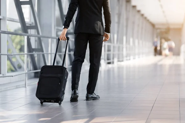 Recortado de hombre de negocios caminando por el aeropuerto con maleta, vista trasera — Foto de Stock