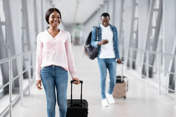 Travel Insurance Concept. Cheerful Black People Walking With Luggages In Airport Terminal — стокове фото