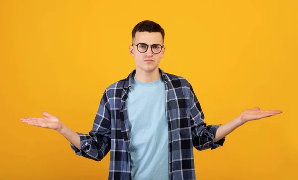 Irritated Caucasian man comparing variants, making scale with his empty hands on orange studio background, panorama — Stok Foto