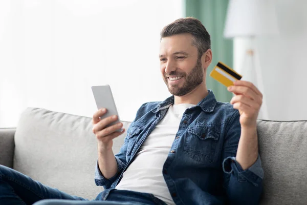 Positive man with smartphone holding credit card — Φωτογραφία Αρχείου