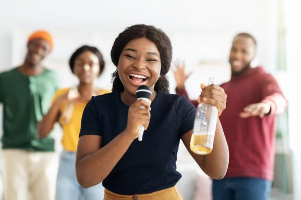 Elinde bira şişesi olan pozitif siyahi kadın karaoke söylüyor. — Stok fotoğraf