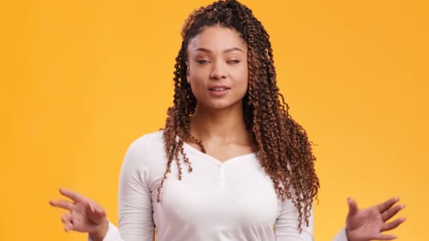 Jovem mulher afro-americana positiva fazendo gesto mudra e meditando, sorrindo e respirando, fundo laranja — Vídeo de Stock