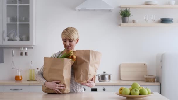 Жена и муж распаковывают сумки после покупки в супермаркете на кухне — стоковое видео
