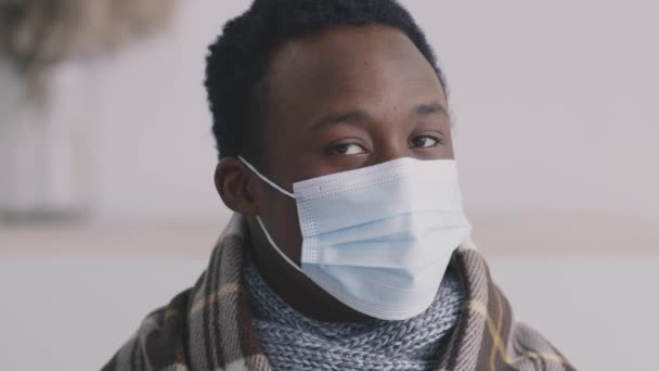 Κοντινό πορτραίτο ενός άρρωστου Αφροαμερικανού με προστατευτική ιατρική μάσκα που γυρίζει πρόσωπο με κάμερα — Αρχείο Βίντεο