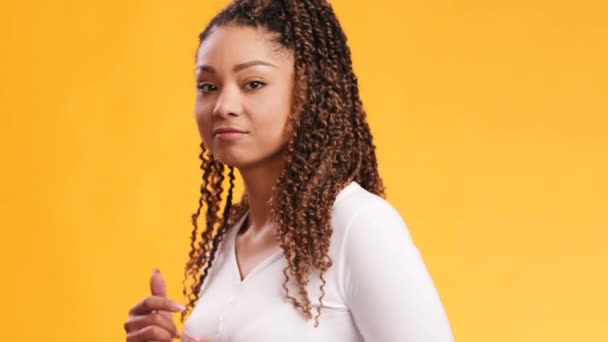 Young flexible african american woman with afro hairstyle moving and flirting, smiling to camera, orange background — Stock Video