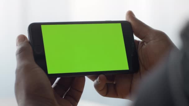 Κινητή τηλεόραση. Κοντινό πλάνο του smartphone με πράσινο chroma οθόνη κλειδί σε μαύρο αρσενικά χέρια, ο άνθρωπος βλέποντας βίντεο σε απευθείας σύνδεση — Αρχείο Βίντεο