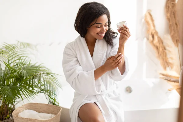 Joven mujer negra aplicando manos crema hidratante piel en el baño —  Fotos de Stock