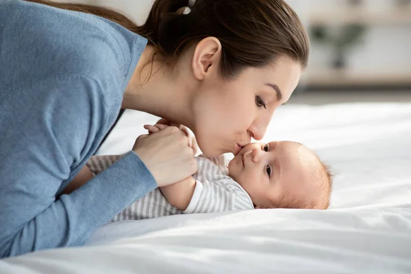 Madres Amor. joven hermosa mujer besos su adorable recién nacido hijo en casa —  Fotos de Stock