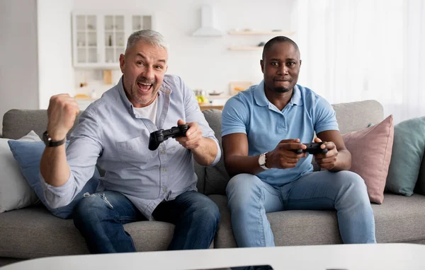 Quem ganha. Consola de vídeo, amigos jogando, se divertindo juntos em casa — Fotografia de Stock