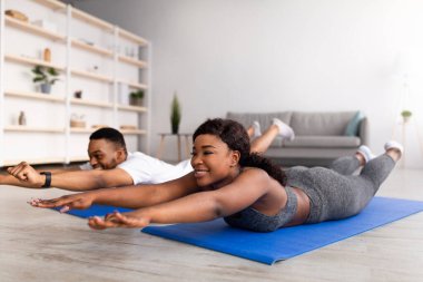 Karantina sırasındaki spor haberleri. Milenyum siyahi çifti spor minderleri üzerinde yoga yapıyor, evde yay asana yapıyor.