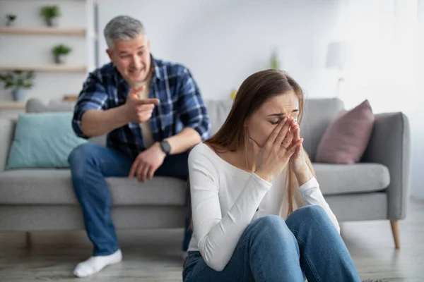 Reife Frau sitzt am Boden und weint, ihr Mann beschuldigt oder beschuldigt sie zu Hause — Stockfoto