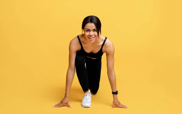 Kardio edzés és kezdés. Boldog fekete nő sport egyenruhában kész futni, elszigetelt sárga háttér, stúdió lövés — Stock Fotó