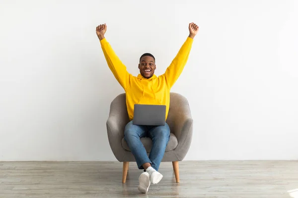 Χαρούμενος Αφρικανός με laptop που τρέμει τις γροθιές του πάνω από το γκρι τοίχο — Φωτογραφία Αρχείου